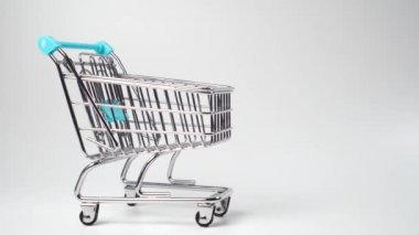 Alışveriş arabası, beyaz arka planda mavi saplı bir şekilde yaklaşıyor. Dolly vurdu. Minyatür oyuncak