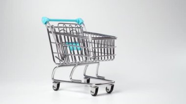 Beyaz arka planda boş bir süpermarket arabası var. Tüketim ve mevsimsel indirimler kavramı