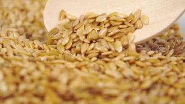 Keten tohumları tahta bir kaşıktan dökülür. Ağır çekim. Makro