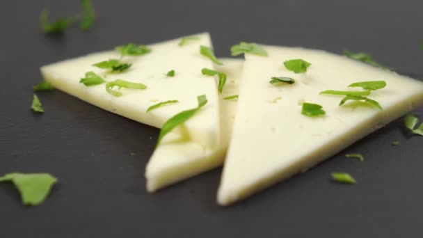切碎的新鲜欧芹的特写落在羊乳酪上 在一块黑色的石头表面上慢动作Dolly Shot — 图库视频影像