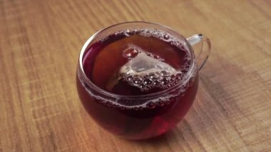 Şeffaf bir çay fincanında siyah çay poşeti demlemek. Doğal sıcak aromatik sağlıklı canlandırıcı buharlı içecek. Kapat.