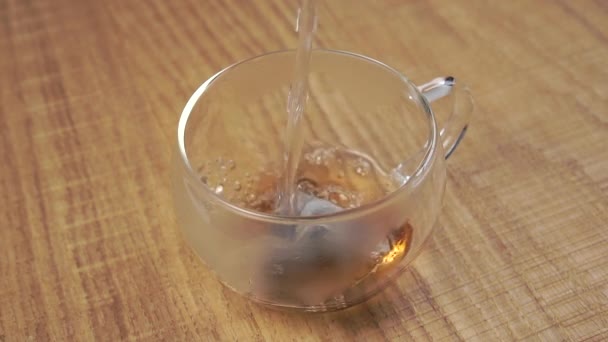 用红茶袋把开水倒入透明的杯子里 酿造一种香醇的饮料 玻璃杯雾化了 靠近点慢动作 — 图库视频影像