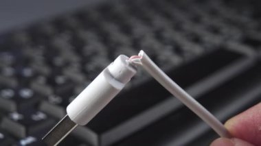 Görüntü olarak siyah bir PC klavyenin arka planında USB fişi olan kırık bir bilgisayar kablosu. Makro çekim