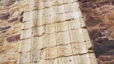 Kilisenin taş duvarının yıpranmış eski sütunları. Antika dokular. Kapat.