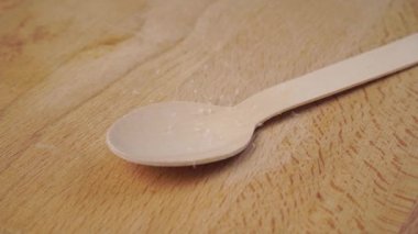 Beyaz şeker kristalleri yavaş çekimde tahta bir kaşığa düşer. Dolly vurdu.