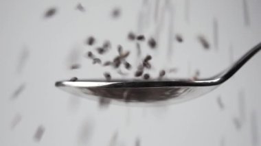 Chia tohumlarının düşüşünü ve kaşıktan sekişini kapat. Makro. Ağır çekim. Kaotik zıplama