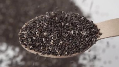 Chia tohumları tatlı olarak ahşap bir kaşığa serpilmiş. Yaklaş. Bulanık tohumlar. Makro. Yavaş çekim