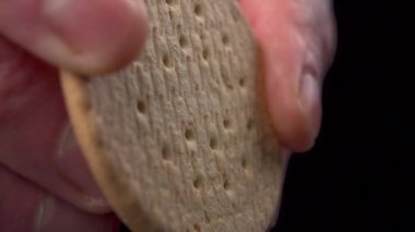 Parmaklar siyah arka planda kurabiyeleri yavaş çekimde kırıyor. Makro çekim