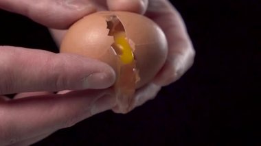 Kapalı çekimde yumurta sarısı ve beyaz yumurta kabuklarını siyah arka planda pişirmek için dökerler. Yavaş çekim