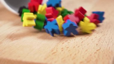 Ahşap yüzeye renkli ahşap figürler saçılmış. Ağır çekimde beyaz bir bardaktan düşmek. Kapatın. Eşsiz kişilik konsepti