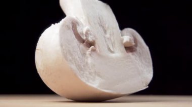 Şampiyon mantarının siyah arka planda tahta kesme tahtasındaki parlak bıçakla makro çekimi.