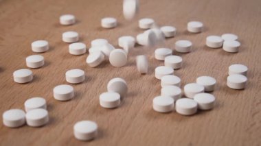 Yuvarlak haplar düşer ve yavaş çekimde ahşap bir yüzeye saçılırlar. Tıp konsepti