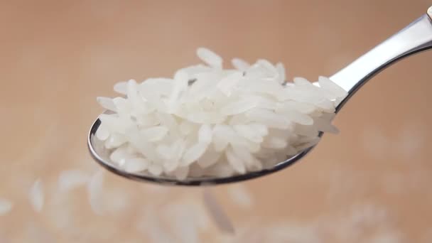 Ungekochte Weiße Reiskörner Fallen Einen Löffel Auf Einem Hölzernen Hintergrund — Stockvideo
