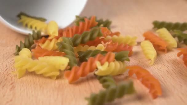 Flerfärgad Pasta Spills Vit Kopp Ett Träbord Närbild Långsamma Rörelser — Stockvideo