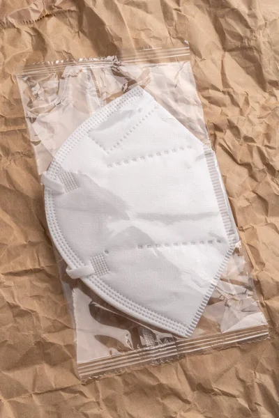 医療用マスクKn95は プラスチック包装のしわのある紙の上に閉じ込められています ウイルスやほこりから保護するための白いマスク オンライン薬局のコンセプト — ストック写真