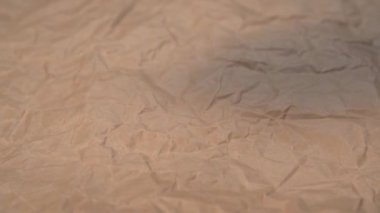 KN95 solunum maskesi plastik bir paketin içinde buruşmuş kraft kağıdına yavaş çekimde düşmek. Yakın plan.