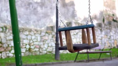 Terk edilmiş eski bir parkta terk edilmiş bir salıncak. Aşırı büyümüş taş bir duvar ve banka karşı sallanan bir salıncak koltuğu. Eski görünüm