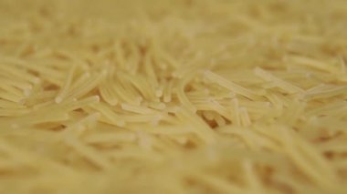 Pişmemiş ince vermicelli, dönüşümlü olarak yavaş çekimde yığının içine düşer. Makro atış. Seçici odak