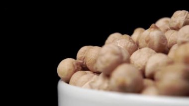 Nohut tohumları beyaz bir kaseyi ağır çekimde doldurur. Makro çekim