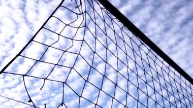 Voleybol ağının silueti, parlak gökyüzünün sirrus bulutlarının arka planına karşı.