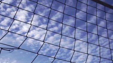 Bulutlu mavi gökyüzü arkaplanındaki hasır voleybol ağı