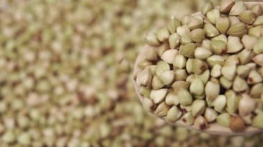 Tahta kaşıktan çiğ karabuğday döküyorum. Biyolojik ürün. Döndürme. Ağır çekim. Doğal sağlıklı gıda konsepti