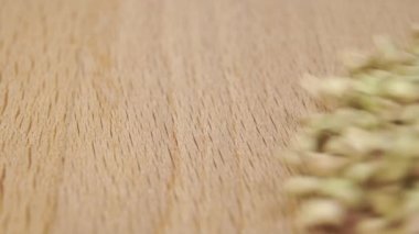 Sağlıklı, pişmemiş bir karabuğday tanesi yavaş çekimde ahşap bir yüzeye düşer. Sağlıklı gıda konsepti