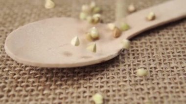 Yeşil karabuğday taneleri yavaş çekimde tahta kaşığa düşer. Makro çekim