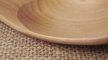 Biyolojik ürün. Yeşil, tahta bir kaşıkta çuvalın üstünde pişmemiş karabuğday. Düşen çiğ karabuğday taneleri. Çuval bezi dokusu. Makro. Yavaş çekim