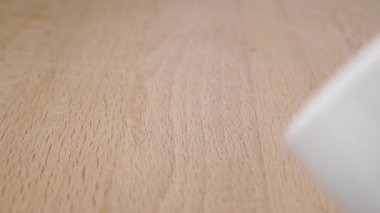 Beyaz bir kaseden ahşap bir yüzeye yavaş çekimde pişmemiş yeşil karabuğday serpiştirmek. Yakın plan. Biyolojik sağlıklı yiyecek.