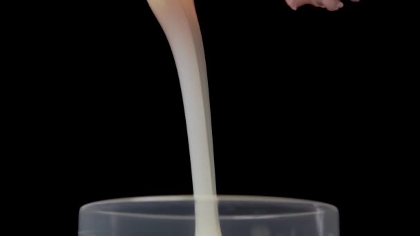 液体洗涤剂以慢动作倒出 并在黑色背景上溢出一个测量杯 宏观射门 — 图库视频影像