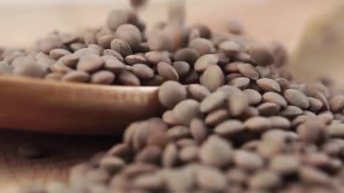 Pişmemiş kuru mercimekleri yavaş çekimde tahta bir kaşığa düşürmek. Makro çekim