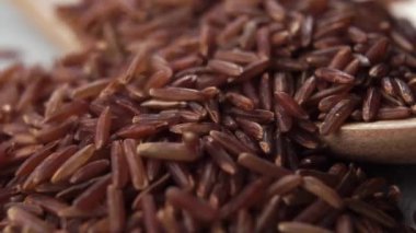 Tahıllı pirinç yavaş çekimde bir yığın içine düşer. Makro. Geleneksel Asya lezzeti. Çiğ pişmemiş diyet kırmızı pirinç. Doli Vuruşu