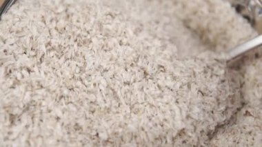 Psyllium kabuklarını kaşıkla karıştırıp bardağa dolduruyorlar. Makro atış. Ağır çekim. Temizlik ve şifa için bitkisel takviye