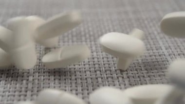 Beyaz oval haplar desenli plastik yüzeye düşer. Makro. Ağır çekim. Virüs Koruma Konsepti