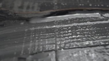 Bir fırçayla desenli bir yüzeye siyah boya çizip boyamak. Yağlı vuruşlar. Makro atış. Yaratıcılık kavramı