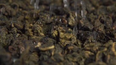 Kuru yeşil barut yaprağı çayı demliyorum. Su yavaş çekimde sulama ve spreyleme ile doluyor. Makro çekim.