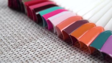 Tırnak cilası örnekleri paleti farklı parlak renklerde. Plastik uçlardaki örneklerde renkli moda manikür. Hasır peçete. Makro. Doli Vuruşu