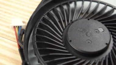 Siyah plastik pervaneler yakından dönüyor. Laptop için yedek parça. Makro atış. Kablolar ve fişler bulanık. Elektronik havalandırma ve soğutma konsepti