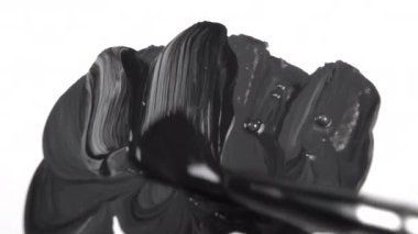 Boya fırçası, beyaz bir tuvale kalın vuruşlarla siyah boya çizer. Yaratıcılık sanatı konsepti