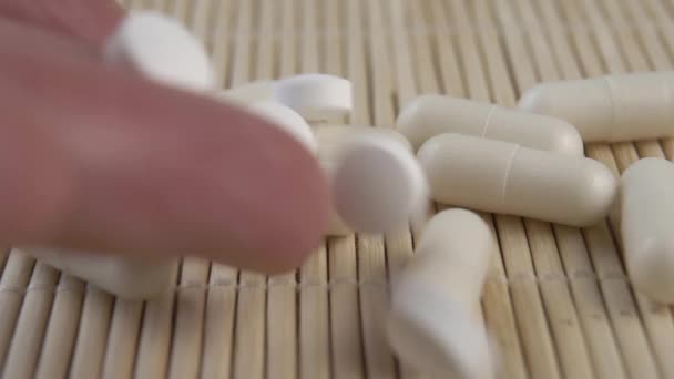 白色药丸从手中倒入竹席上慢动作的一堆胶囊中 — 图库视频影像