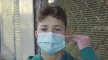 Genç bir adam binanın duvarının yanında tek kullanımlık tıbbi maske takıyor. Coronavirus 'a Karşı Zorunlu Eylem Konsepti