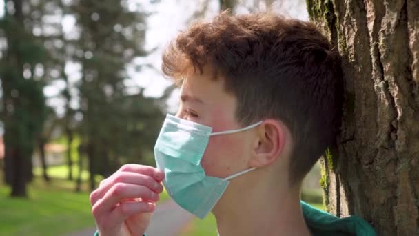Seorang Pemuda Taman Meluruskan Topeng Pelindung Medis Dekat Batang Pohon — Stok Video