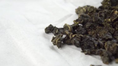 Beyaz kağıt peçetenin üzerinde kurumuş barut yeşil çay yaprakları. Makro. Dolly vurdu. Geleneksel Çin içeceği.
