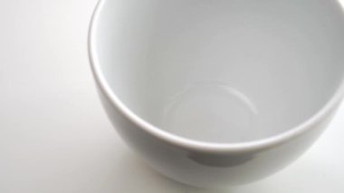 Süblimleşmiş kurutulmuş hindiba kökü bir çay kaşığından beyaz bir masanın üzerindeki boş bir fincana dökülür. Ağır çekim. Ekolojik doğal aromatik sağlıklı biyolojik içecek.