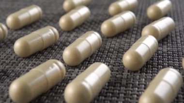 Bitki tozu içerikli homeopatik kapsüller gri plastik desenli bir yüzey üzerinde sıralanmış. Makro. Doli Vuruşu