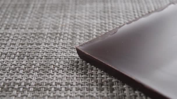 Una Rebanada Chocolate Amargo Oscuro Cerca Una Estera Plástico Macro — Vídeo de stock