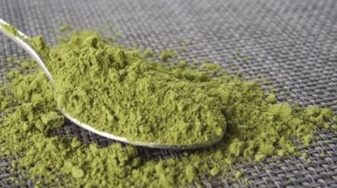 Bir çay kaşığı kibrit çayını desenli gri paspasa yakın çekim yap. Makro. Dolly vuruldu. Geleneksel Japon çayı