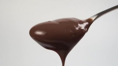 Hafif arka planda çikolata kremalı çay kaşığı. Yakından yavaşça damlıyor. Makro çekim