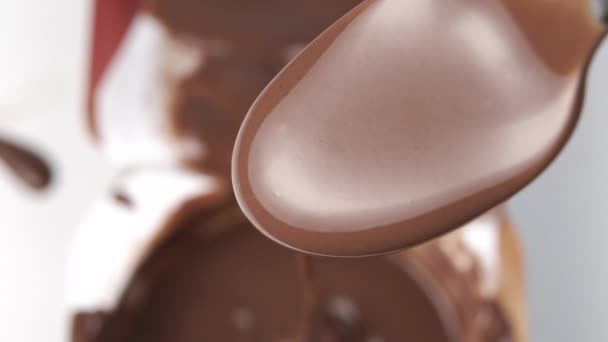 满勺的液体巧克力关门了 将慢速运动的液体倒入模糊的塑料包装中 巧克力慕斯甜点 — 图库视频影像